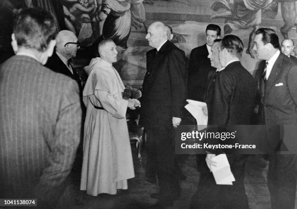 Le 19 décembre 1963, au Palais de l'Elysée, le Président de la République de Gaulle serre la main du Père Carré avant de saluer l'architecte Le...