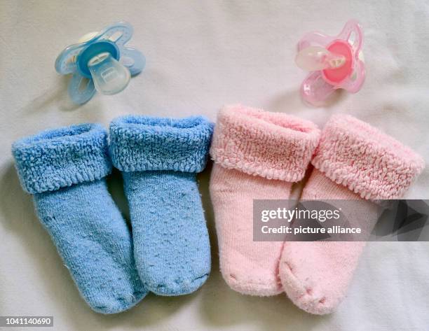 Pink and blue socks and matching pacifiers lie in a baby bed in Frankfurt , Germany, 14 April 2015. Photo: Patrick Pleul/dpa | usage worldwide