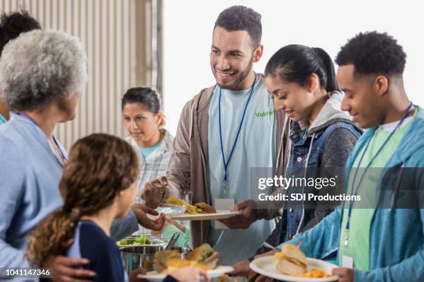 young man enjoys serving meals at soup kitchen - homeless shelter man stock pictures, royalty-free photos & images