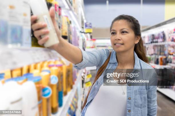 mujer elige loción en el supermercado - bolsa de cor creme fotografías e imágenes de stock