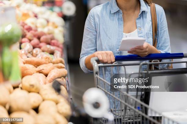onherkenbaar vrouw kiezen van producten in supermarkt - boodschappenlijst stockfoto's en -beelden