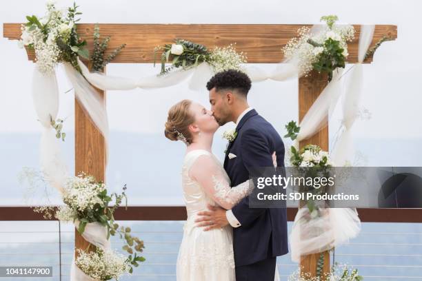 bride and groom kissing in front of wedding altar - altare stock pictures, royalty-free photos & images