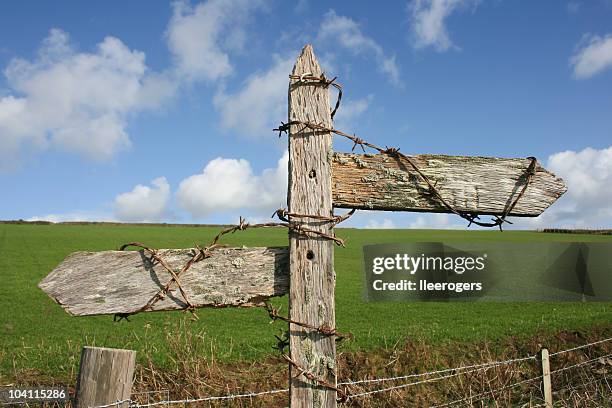 illegible signpost with barbed wire looking weathered - crossroads sign stock pictures, royalty-free photos & images