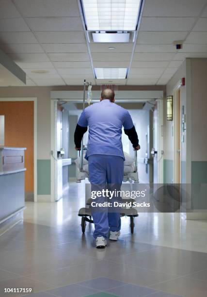 male nurse pushing gurney in hospital - hospital gurney stock pictures, royalty-free photos & images