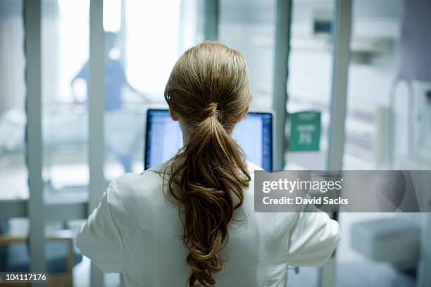 female doctor using laptop in hospital, rear view - doctor technology stockfoto's en -beelden