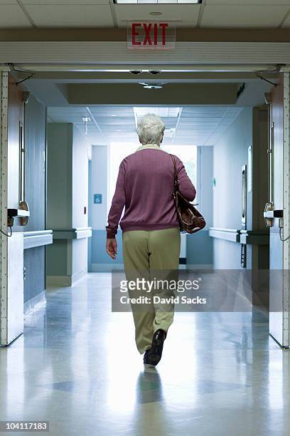 woman walking out hospital exit - partire foto e immagini stock