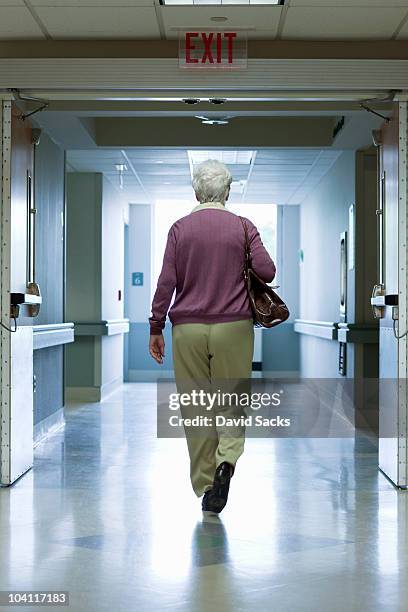 woman walking out hospital exit - só uma mulher idosa imagens e fotografias de stock