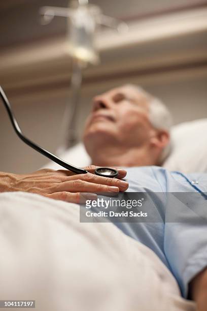 doctor checking man's heartbeat with stethoscope - stethoscope heart stock-fotos und bilder