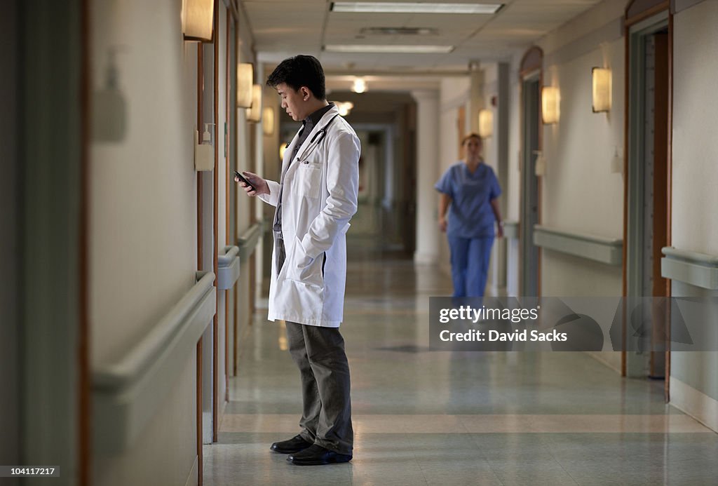 Asian doctor in hospital corridor with phone