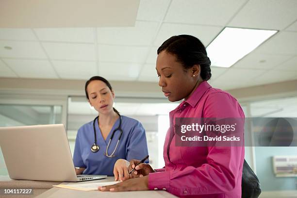 aa woman filling out forms at hospital - administrative professional stock pictures, royalty-free photos & images