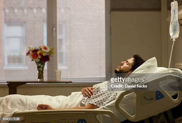man in hospital bed holding his side - man in hospital stock pictures, royalty-free photos & images