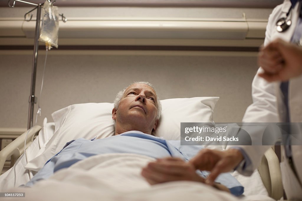 Man in hospital bed having pulse taken