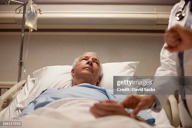 man in hospital bed having pulse taken - man in hospital stock pictures, royalty-free photos & images