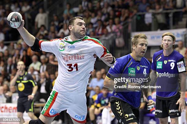 Bartosz Jurecki of Magdeburg scores against Oliver Roggisch and Borge Lund of Rhein Neckar Loewen during the Toyota Handball Bundesliga match between...