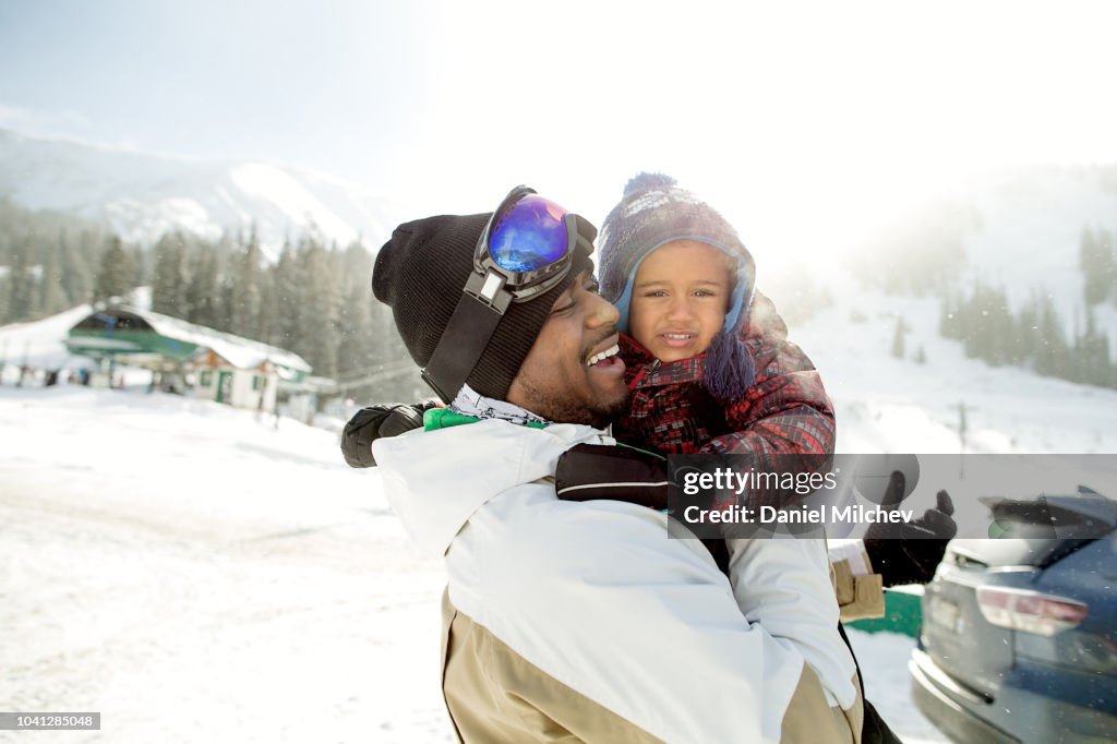 Happy multi-ethnic father and son at a ski resort getting ready to go skiing.