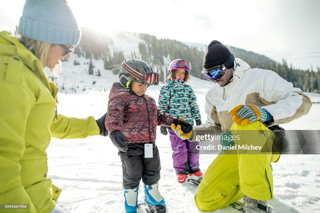 Mixed race family teaching their young boy to ski at a winter ski resort in Colorado.
