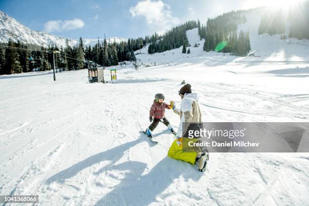 father giving high five to his young boy during a ski lesson at a winter resort in colorado. - colorado skiing stock pictures, royalty-free photos & images