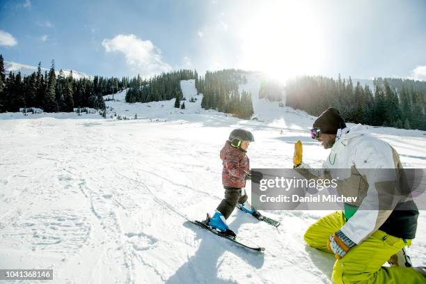 happy father giving high five to his young boy as he is teaching him how to ski during the winter. - skidsemester bildbanksfoton och bilder