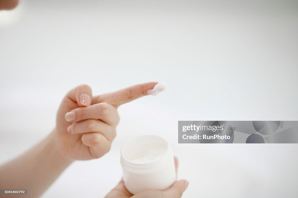 Young woman with moisturizer on fingertips