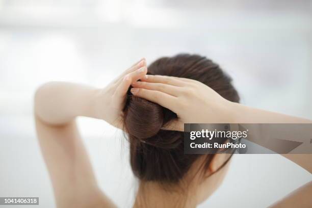woman making hair bun - hair bun stockfoto's en -beelden