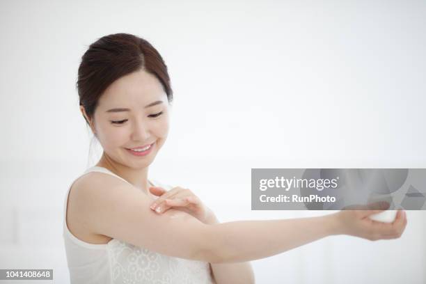 young woman applying cream on arm - beauty treatment ストックフォトと画像