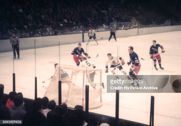 Goalie Gump Worsley of the New York Rangers poke checks the puck away from Ed Kachur of the Chicago Blackhawks during an NHL game circa 1958 at the...