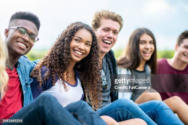 university friends sit next to each other on the grass and smile - cliqueimages stock pictures, royalty-free photos & images