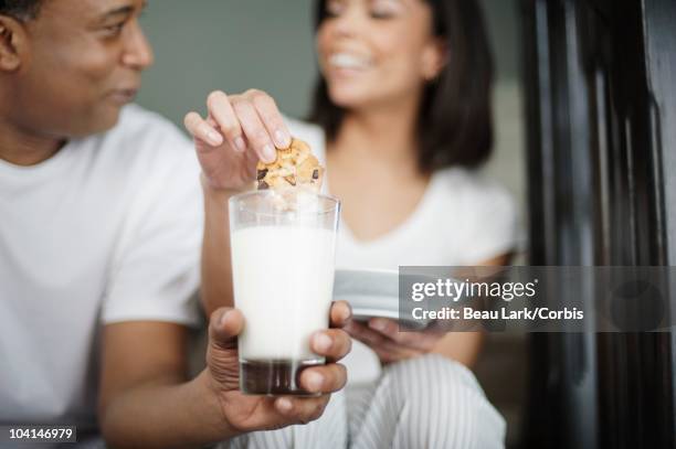 couple dipping cookie in milk - 2 männer essen kekse stock-fotos und bilder