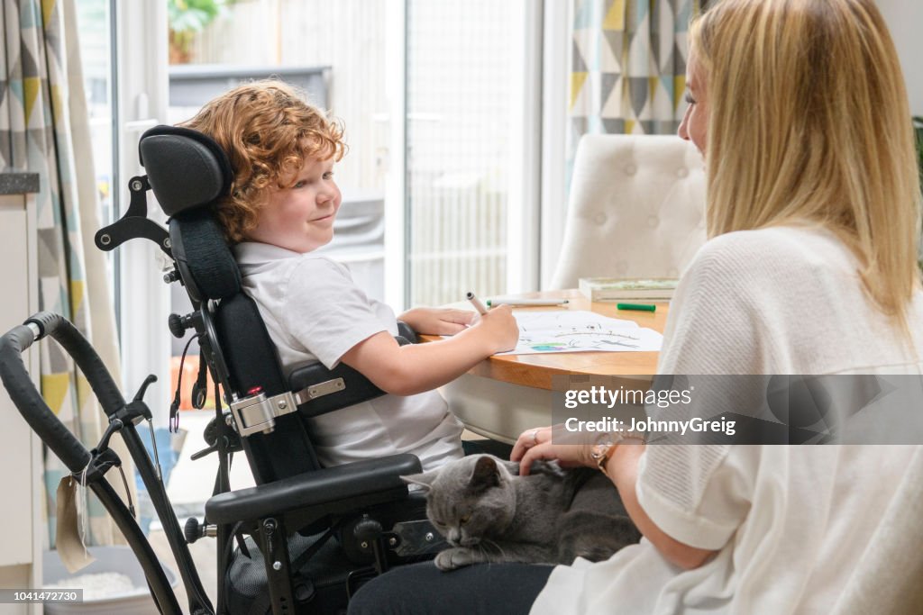 Mother and son in wheelchair with disability at home