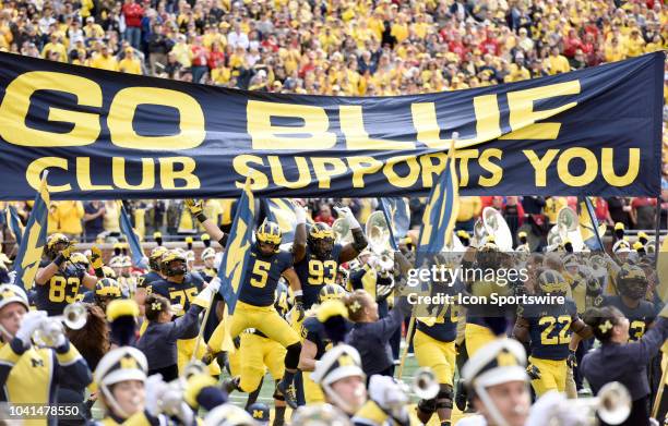 Michigan's football team jumps up to touch the M Go Blue Club banner at midfield before their 56-10 win over the Nebraska Cornhuskers in a college...