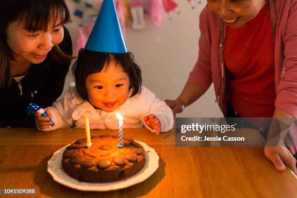 child eager to blow the candles from her birthday cake with mother and grandmother - chinese birthday stockfoto's en -beelden