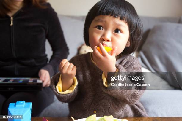 child eating an orange from fruit bowl - auckland food bildbanksfoton och bilder