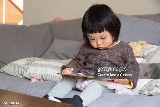 child looking at and playing on tablet device - bottomless girls stockfoto's en -beelden