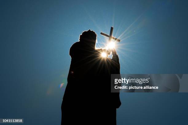 The Mattielli statue at the Dresden Cathedral, Maria Magdalena of Pazzi, appears as a dark silhouette in front of a blue sky during the solar eclipse...