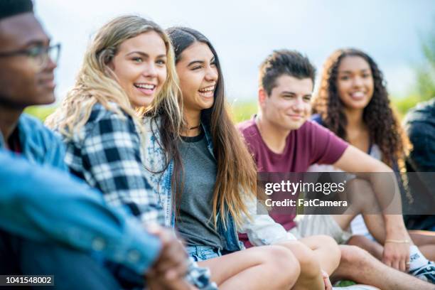 young adult friends laughing together on the grass - junior stock pictures, royalty-free photos & images