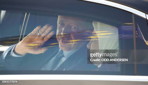 Turkish President Recep Tayyip Erdogan waves as he sits inside a car with his wife Emine Erdogan as a European flag is reflected on the car window...