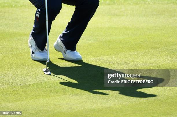 Golfer Tiger Woods casts a shadow on a green as he prepares to putt during a practice session ahead of the 42nd Ryder Cup at Le Golf National Course...
