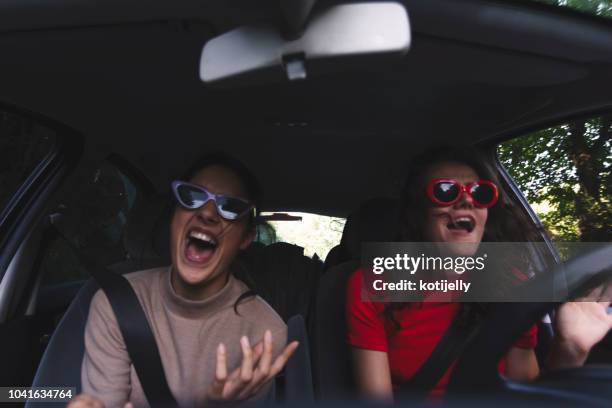 dos mujeres jóvenes felices divirtiéndose en el coche - crazy car fotografías e imágenes de stock