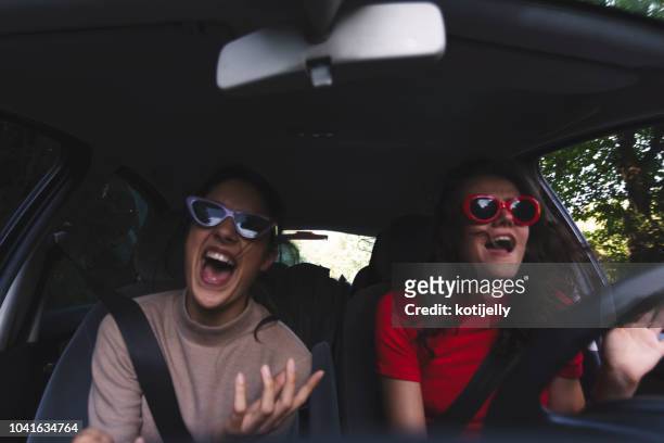 two happy young women having fun in car - singing stock pictures, royalty-free photos & images