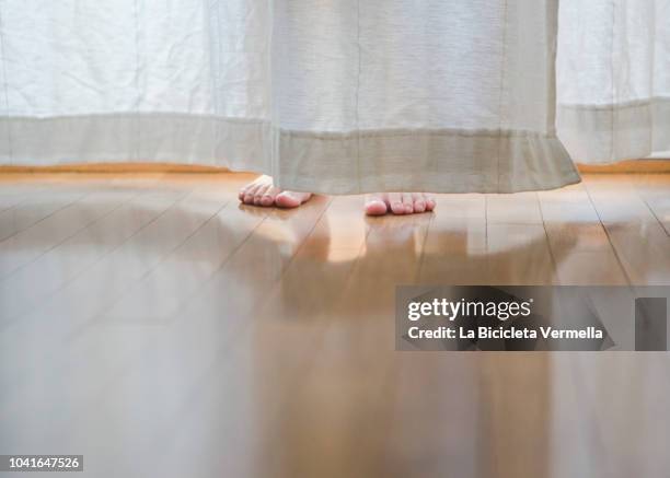 child hiding behind the curtain - hide stock-fotos und bilder