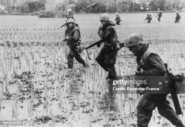 Quelques soldats du 4e régiment de marines américains traversant des rizières, au Vietnam, le 10 mars 1967.