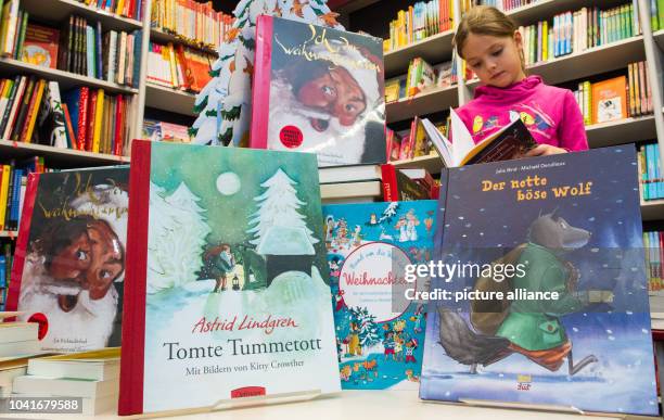 Amy thumbs through a book behind three new children's books for Christmas, "Der nette boese Wolf" by Belgium's Michael Derullieux, Astrid Lindgren's...