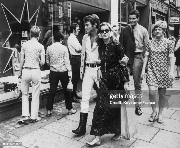 Couple marchant dans les rues de Chelsea, la femme est pieds nus et porte une robe longue, l'homme est en pantalon blanc et bottes noires, à Londres,...
