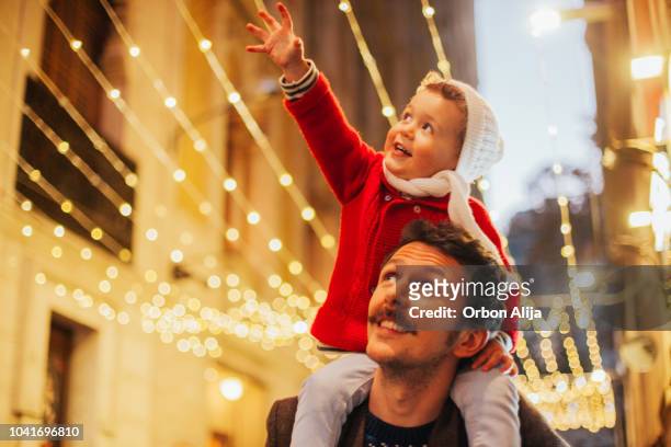 vader en zoon kijken de kerstverlichting - christmas scenes stockfoto's en -beelden