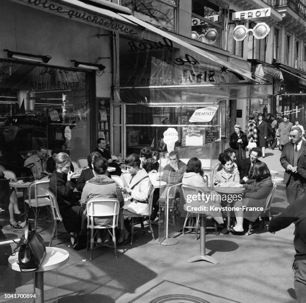 Terrasse de café bondée avec l'apparition du soleil à Paris, France, le 7 avril 1964.