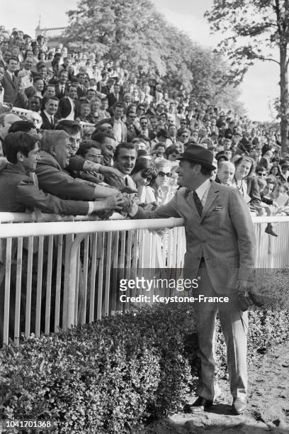 Eddie Constantine, souriant, serre les mains d'un public chaleureux à Longchamp, à Paris, France, le 26 juin 1967.