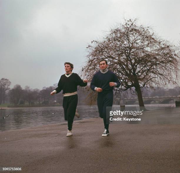 Composer Lionel Bart out jogging with actor Terence Stamp beside the Serpentine in Hyde Park, London, circa 1961.