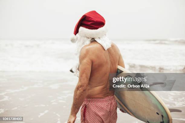 kerstman met surfplank - christmas summer stockfoto's en -beelden