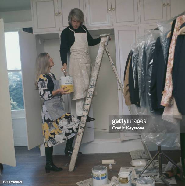 English pop singer Adam Faith decorating at home with his wife Jackie Irving, UK, circa 1970.