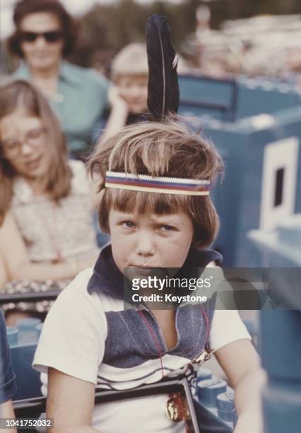 Frederik, Crown Prince of Denmark, wearing a feather headdress at a fun centre, 1977.